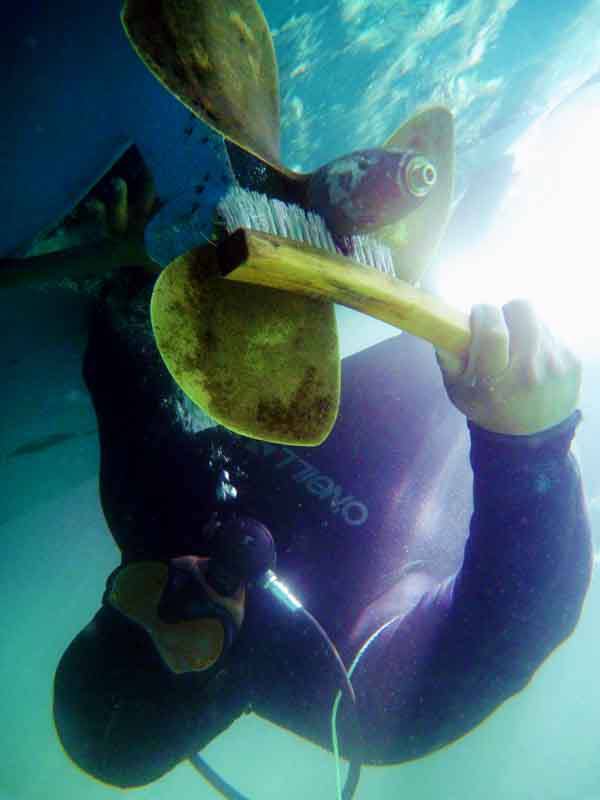 Diver cleaning boat propeller underwater